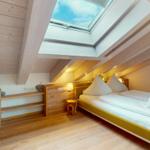 Schlafzimmer mit Dachschrägen, Dachfenster und Holzmöbeln.