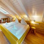 Schlafzimmer mit Dachschrägen, Bett und Schreibtisch.