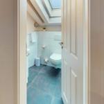 Badezimmer mit Toilette, blauen Fliesen und Dachfenster.