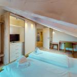 Schlafzimmer mit Bett, Kleiderschrank und Schreibtisch unter Dachschrägen.