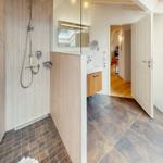 Dusche mit Glaswand, Waschbecken und Blick in das Zimmer.
