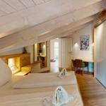 Schlafzimmer mit Dachschrägen, Bett, Schrank und Schreibtisch.