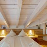 Schlafzimmer mit Holzboden, Bett und eingebauten Nachttischen mit Beleuchtung.