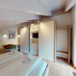 Schlafzimmer mit Doppelbett, Kleiderschrank und Fenster. Blick auf Balkon und Holzbalkendecke.