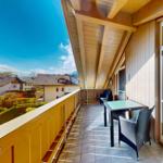 Terrasse mit Tisch und Stühlen, Holzverkleidung und Blick auf Wohnhäuser.