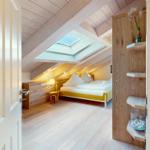 Schlafzimmer mit Dachschrägen, Dachfenster und gelbem Bett