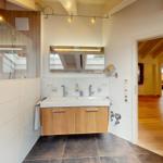 Badezimmer mit Dusche, Waschbecken und Blick in Schlafzimmer