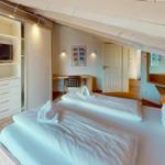 Zwei Betten mit weißen Bettwäsche, Schrank mit Fernseher und Schreibtisch mit Stuhl.