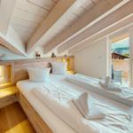 Schlafzimmer mit Doppelbett, Holzdecke und Balkonansicht.