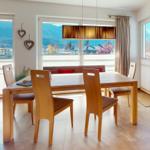 Esszimmer mit Holztisch, Stühlen und Blick auf Berge.