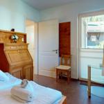Schlafzimmer mit Holzbett, Schreibtisch und Blick auf Balkon.