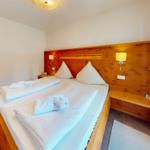 Schlafzimmer mit Holzbett, weißen Bettwäsche und integrierten Nachttischen.