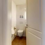 Badezimmer mit Toilette, Dusche und Toilettenpapierhalter. Bodenfliesen und weiße Wände.