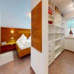 Schlafzimmer mit Holzbett und Kleiderschrank. Fenster mit Pflanze und Licht.