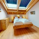 Schlafzimmer mit Doppelbett, Holzmöbel und Dachfenster.