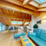 Wohn- und Essbereich mit Holzboden, blauem Sofa und Dachfenstern.