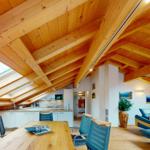 Dachgeschosswohnung mit Holzdecke, Essbereich und Wohnbereich mit Sofa.