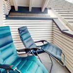Zwei blaue Liegestühle auf einer Terrasse neben einem Haus mit weißen Schindeln.