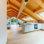 Küche mit Holzboden und Dachschrägen. Durchgang zum Essbereich mit Tisch und Stühlen.