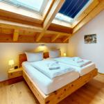 Schlafzimmer mit Doppelbett, Holzboden und Dachfenstern. Wandbild und Spiegel sind vorhanden.
