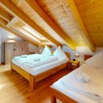 Zimmer mit zwei Betten, Holzboden und Holzdecke mit Balken.