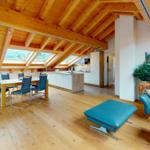 Wohn- und Essbereich mit Holzdecke, Küchenzeile und Sofa.