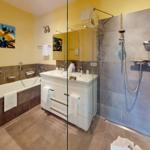 Badezimmer mit Badewanne, Dusche und Waschtisch. Wandbild mit Zitronen.