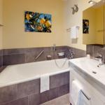 Badezimmer mit Badewanne, Waschbecken und Spiegel. Wandbild mit Zitronen.
