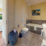 Badezimmer mit Badewanne, Waschbecken und Toilette. Durchgang zur Schlafzimmer mit Bett.