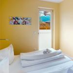 Ein Schlafzimmer mit Bett, Wandbild und Tür zum Balkon.
