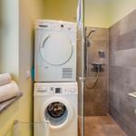 Waschmaschine und Trockner in einem Badezimmer mit Dusche und Handtüchern.