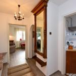 Hausflur mit Spiegel, Küche und Blick in Wohnzimmer.