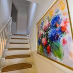 Treppenhaus mit weißer Treppe und buntem Wandbild.