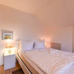 Schlafzimmer mit Bett, Nachttisch und Lampen. Holzboden und Schrankschrank.