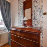 Holzschrank mit Spiegel und Lampe vor floraler Tapete