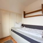 Schlafzimmer mit Bett, Kleiderschrank und Wandregal.