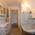 Badezimmer mit Waschbecken, Spiegel und Fliesenboden
