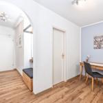 Flur mit Holzboden, Schreibtisch und Wandbild mit Hirsch. Türen und Bänke sind sichtbar.