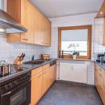 Küche mit Holzschränken, Edelstahlherd und Fenster mit Pflanze.