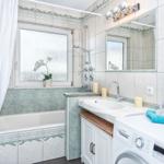 Bad mit Badewanne, Dusche, Waschmaschine und Spiegel.