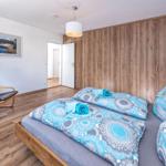 Schlafzimmer mit Bett, Kleiderschrank und Sessel. Bild an der Wand.