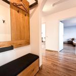 Eingangsbereich mit Holzgarderobe und Sitzbank. Durchgang zu Schlafzimmer und Wohnbereich.