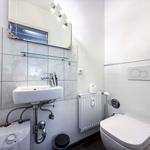 Badezimmer mit Waschbecken, Spiegel und Toilette. Wandheizung und Heizungsgerät sichtbar.