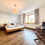 Schlafzimmer mit Holzboden, Bett, Sessel und Fenster mit Blick.