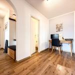 Ein Raum mit Holzboden, Schreibtisch, Stuhl und Wandbild eines Hirsches.