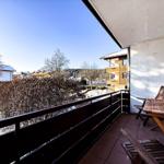 Terrasse mit Holztisch und Stühlen, Blick auf verschneite Landschaft und Gebäude.