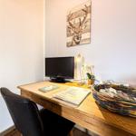 Schreibtisch mit Monitor, Stuhl und Wandbild eines Hirsches.