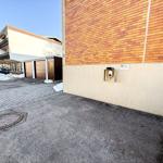 Einfahrt mit Garagen und Schneehaufen vor einem Gebäude mit Backsteinfassade.