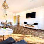 Wohn- und Essbereich mit Holzboden, Fernseher und Esstisch.