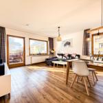 Wohn- und Essbereich mit Holzboden, Sofa, Esstisch und TV.